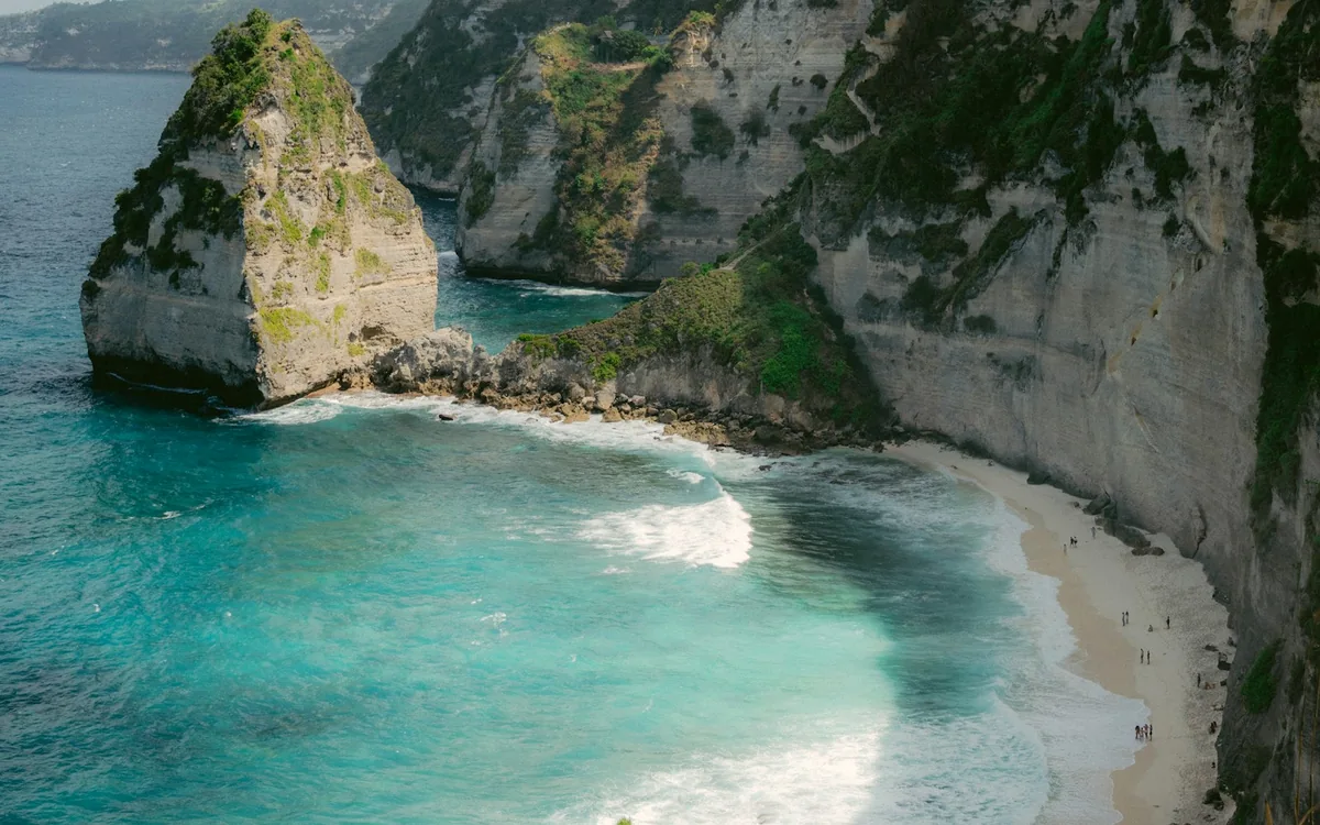 Limestone cliffs above turquoise waves and a white sand beach in Bali, Indonesia